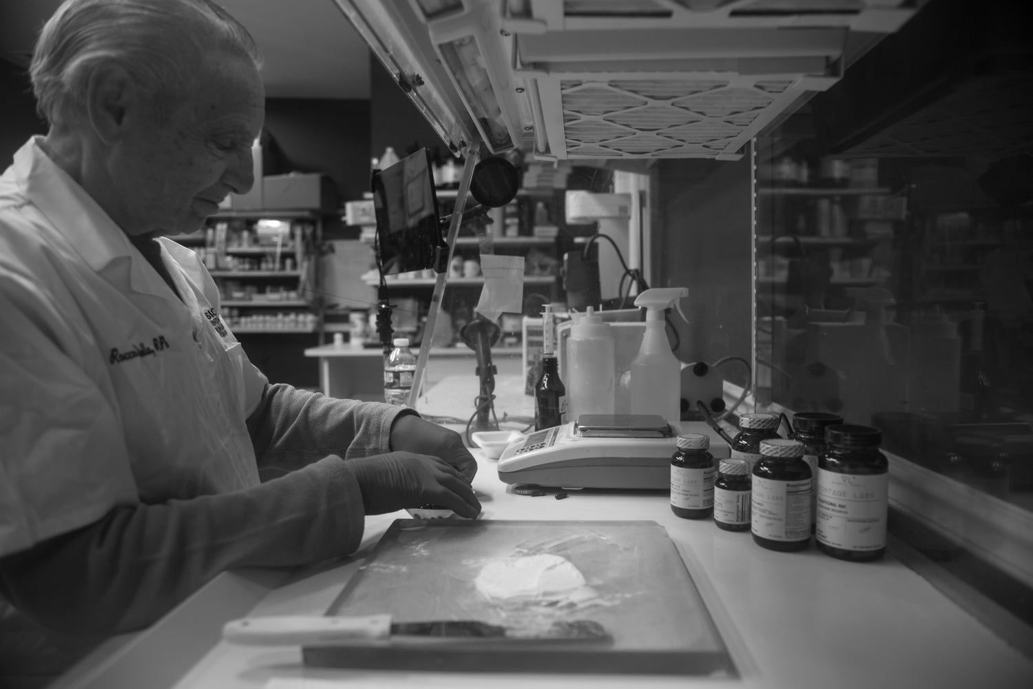 Person working at a counter in a pharmacy with various items on the counter.